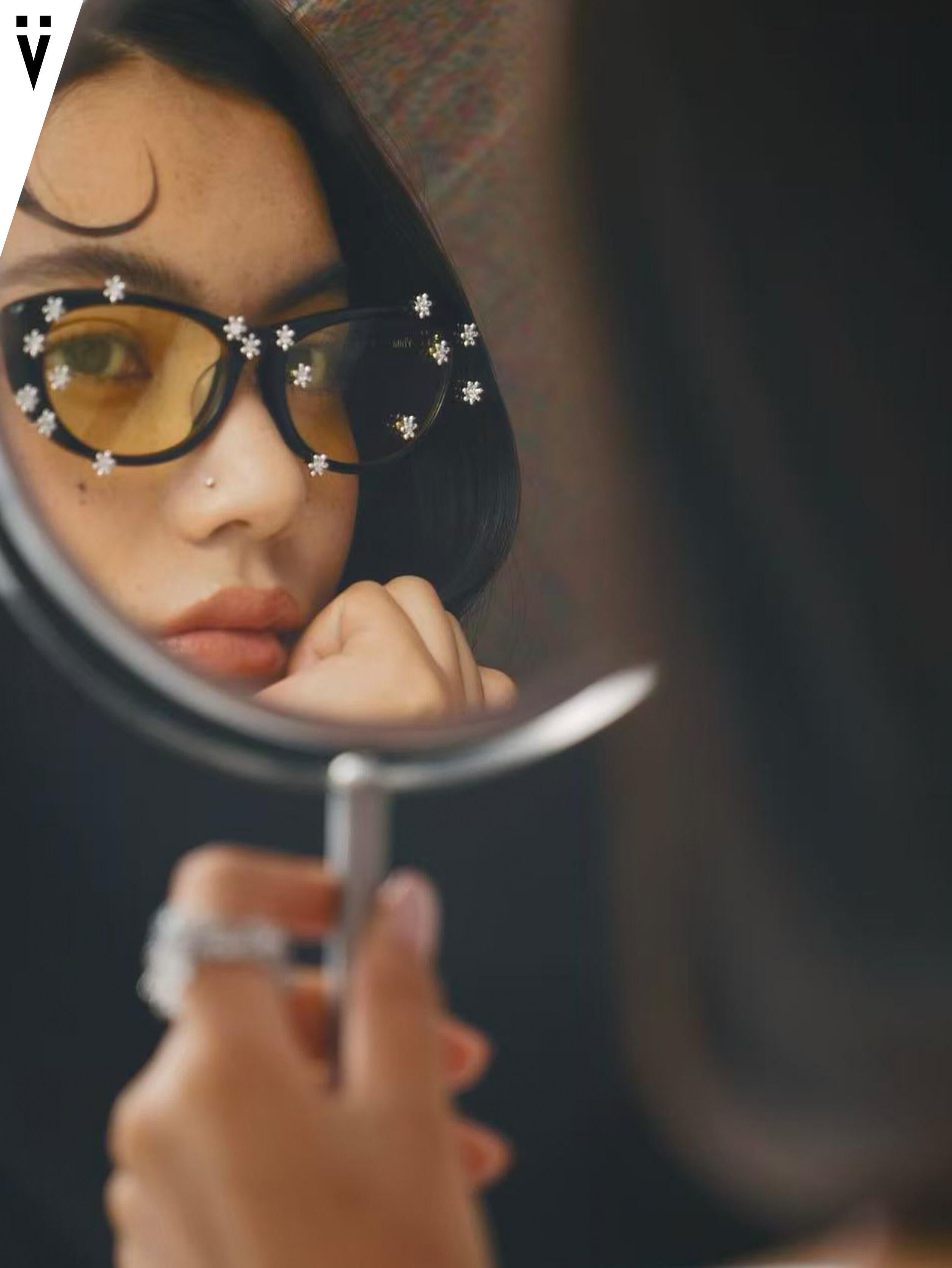 Floral sunglasses reflected in a handheld mirror