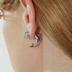 YVMIN island/interlocking dolphin stud earrings featuring silver-tone dolphin designs on post backings.